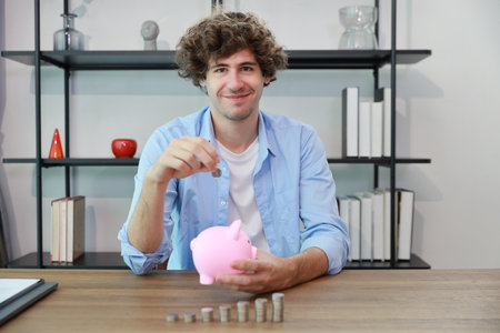 Caucasian businessman putting coin into piggy bank with saving growth on stacking coin growing, meaning of earning money or investment or financial or tax for business advertising conceptの写真素材