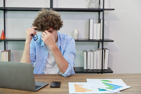 Young adult businesswoman touching his head on table in office after bad news business failure or get fired and feeling discouraged, distraught and hopeless in modern office.の写真素材