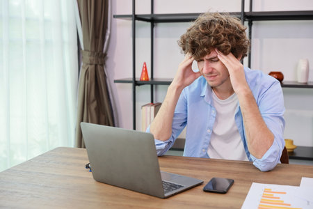 Young adult businesswoman touching his head on table in office after bad news business failure or get fired and feeling discouraged, distraught and hopeless in modern office.の写真素材