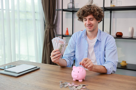 Caucasian businessman putting coin into piggy bank with saving growth on stacking coin growing with banknote, meaning of earn money or investment or financial or tax for business advertising conceptの写真素材