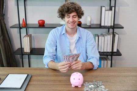 Succeccful caucasian businessman counting banknote with piggy bank and stacking coin on table, meaning of earn money or investment or financial or tax for business advertising conceptの写真素材