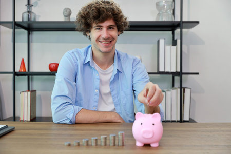 Caucasian businessman putting coin into piggy bank with saving growth on stacking coin growing, meaning of earning money or investment or financial or tax for business advertising conceptの写真素材