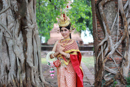 Young fashion and beautiful asian woman in red Thai traditional costume pay respect sawasdee symbol...