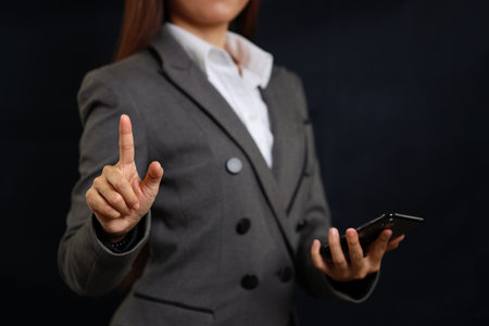 Attractive professional female hands standing and showing and pointing on blank screen on smart mobile phone for advertising on black background isolatedの写真素材