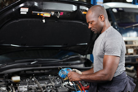 Mechanic in half uniform checking car air conditioning system refrigerant recharge, leak detection, fill refrigerant service.
Concept of car center repair service.の写真素材