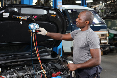 Man technician car mechanic in half uniform checking maintenance a car service at repair garage station. Worker holding wrench and fixing breakdown vehicle. Concept of car center repair service.の写真素材