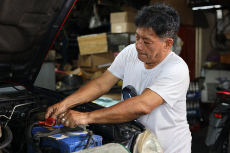 Man technician car mechanic in half uniform checking maintenance a car service at repair garage station. Worker holding wrench and fixing breakdown vehicle. Concept of car center repair service.の写真素材