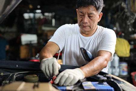 Man technician car mechanic in half uniform checking maintenance a car service at repair garage station. Worker holding wrench and fixing breakdown vehicle. Concept of car center repair service.の写真素材