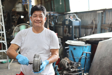 Man technician car mechanic in half uniform checking maintenance a car service at repair garage station. Worker holding wrench and fixing breakdown vehicle. Concept of car center repair service.の写真素材