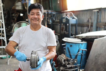 Man technician car mechanic in half uniform checking maintenance a car service at repair garage station. Worker holding wrench and fixing breakdown vehicle. Concept of car center repair service.の写真素材