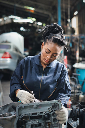 Woman technician car mechanic in uniform checking maintenance car service at repair garage station. Worker holding wrench fixing breakdown vehicle. Concept of car center repair service.の写真素材