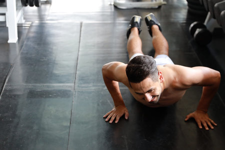 Sporty young adult maman push up on the floor in fitness gym.