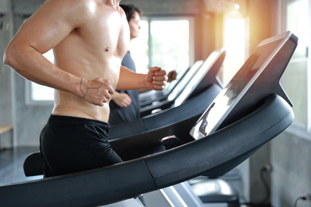 close up image of healthy and handsome caucasian muscle man in shirtless who running on excerise machine in gymの写真素材