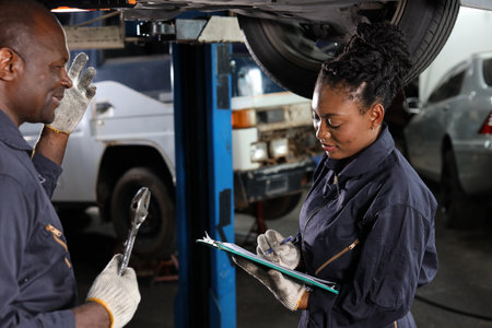 Group of car mechanic in uniform checking maintenance a lifted car service with clipboard at repair garage station. Worker holding wrench and fixing breakdown vehicle. Car repair service conceptの写真素材