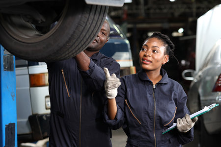 Group of car mechanic in uniform checking maintenance a lifted car service with clipboard at repair garage station. Worker holding wrench and fixing breakdown vehicle. Car repair service conceptの写真素材