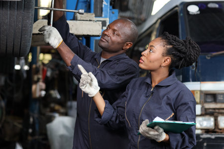 Group of car mechanic in uniform checking maintenance a lifted car service with clipboard at repair garage station. Worker holding wrench and fixing breakdown vehicle. Car repair service conceptの写真素材