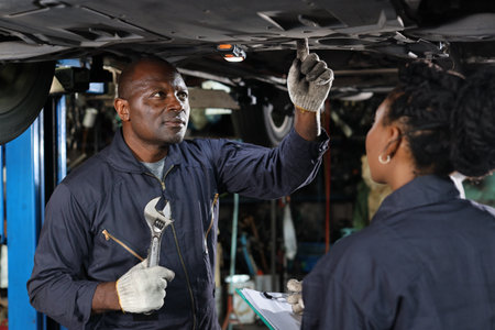Group of car mechanic in uniform checking maintenance a lifted car service with clipboard at repair garage station. Worker holding wrench and fixing breakdown vehicle. Car repair service conceptの写真素材
