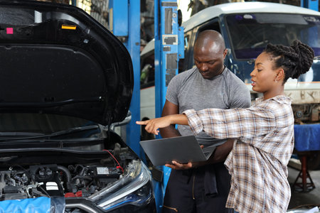 Man technician car mechanical in half uniform show car maintenance service report on computer at repair garage station. Auto mechanic give customer discussion on her vehicle repair problemsÂ conditionの写真素材