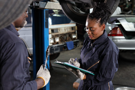 Group of car mechanic in uniform checking maintenance a lifted car service with clipboard at repair garage station. Worker holding wrench and fixing breakdown vehicle. Car repair service conceptの写真素材
