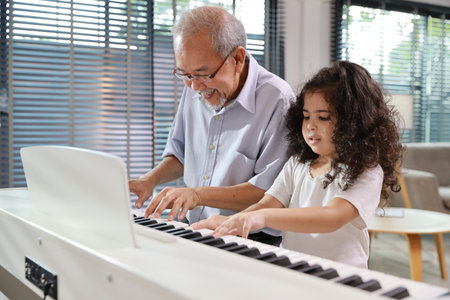Happy smiling asian senior man sitting and playing piano while teaching grandchild in living room house indorrs. Musical and relaxation makes elder male happiness. Health care lifestyle concept.の写真素材