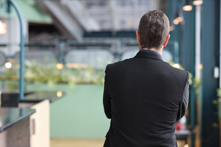 Rear view portrait of caucasian businessman in suit standing and arms cross with confident while looking camera with happy face in modern office. Success business conceptの写真素材