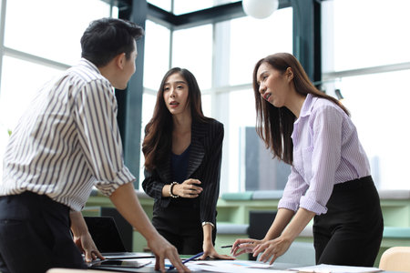 Collaborative process of young asian business people team working together discussing, researching, brainstorming and planning work at business meeting in modern office building and city backgroundの写真素材