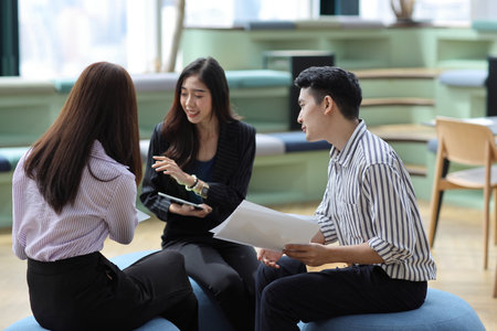Collaborative process of young asian business people team working together discussing, researching, brainstorming and planning work at business meeting in modern office building and city backgroundの写真素材
