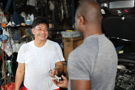 Group of car mechanic men in half uniform checking maintenance a car service at repair garage station. Worker holding wrench and fixing breakdown vehicle. Concept of car center repair service.の写真素材