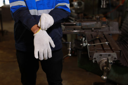 Technician engineer man hands in protective uniform maintenance operation or checking lathe metal machine while putting on engineer gloves at heavy industry manufacturing factory. Metalworking conceptの写真素材