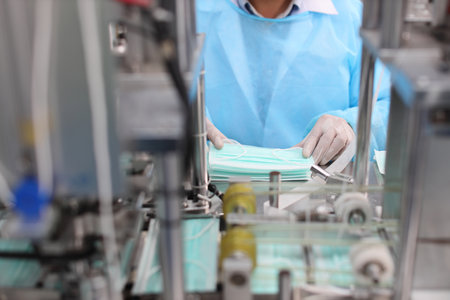 Inspector or worker hands with nitrile gloves doing quality of mask and medical face mask production line, Industry and factory concept.の写真素材