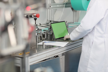 Inspector man or worker male hands doing quality of mask and medical face mask production line with blank green screen computer, Industry and factory concept.の写真素材