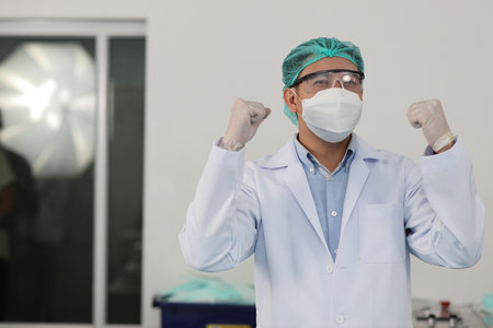 Worker in personal protective equipment or PPE inspection quality raising hands with exciting emotion in mask and medical face mask production line factory, manufacturing industry and factory concept.の写真素材