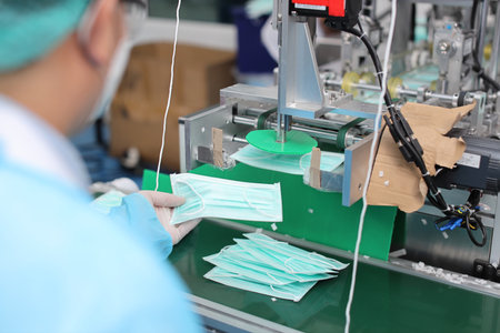 Inspector or worker hands with nitrile gloves doing quality of mask and medical face mask production line, Industry and factory concept.の写真素材