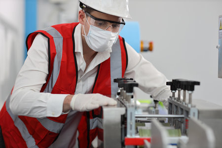 Caucasian mechanic technician maintenance or PPE inspecting quality of mask and medical face mask production line in factory, manufacturing industry and factory concept.の写真素材