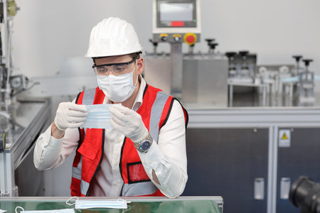 Caucasian mechanic technician maintenance or PPE inspecting quality of mask and medical face mask production line in factory, manufacturing industry and factory concept.の写真素材