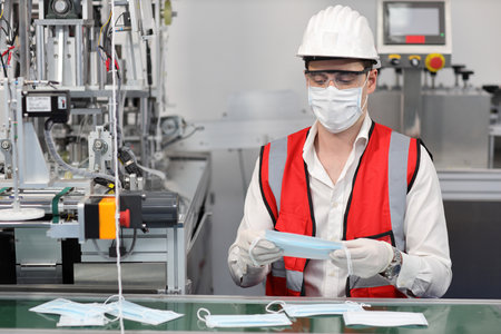 Caucasian mechanic technician maintenance or PPE inspecting quality of mask and medical face mask production line in factory, manufacturing industry and factory concept.の写真素材