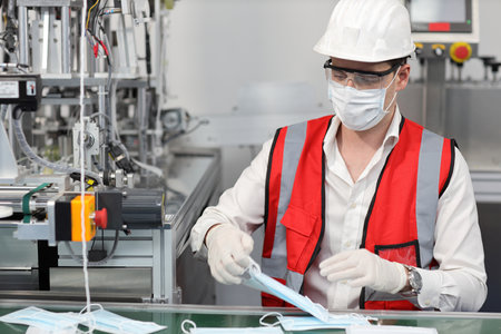 Caucasian mechanic technician maintenance or PPE inspecting quality of mask and medical face mask production line in factory, manufacturing industry and factory concept.の写真素材
