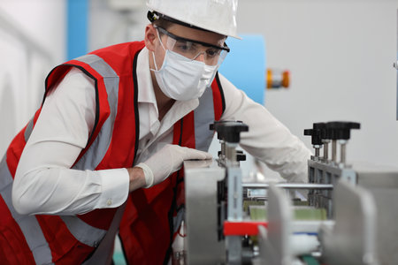 Caucasian mechanic technician maintenance or PPE inspecting quality of mask and medical face mask production line in factory, manufacturing industry and factory concept.の写真素材