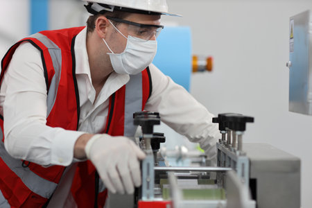Caucasian mechanic technician maintenance or PPE inspecting quality of mask and medical face mask production line in factory, manufacturing industry and factory concept.の写真素材