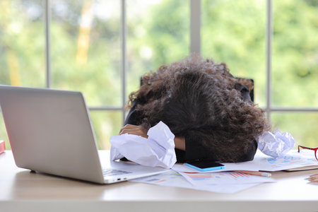 Mid adult businesswoman lying face down on table in office after bad news business failure or get fired and feeling discouraged, distraught, distraught and hopeless in modern office.の写真素材
