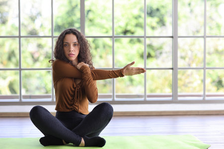 Sporty African American woman sit on yoga mat practicing mediate yoga watching coach training video online from computer. Healthy female doing exercise and taking lesson distant course at homeの写真素材
