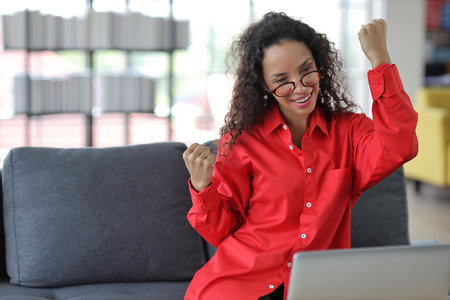Happy woman sitting and using computer and raising hands with happy smiling face while completed business deal in living room
Businesswoman raising hands and exciting emotion with somthing successfulの写真素材