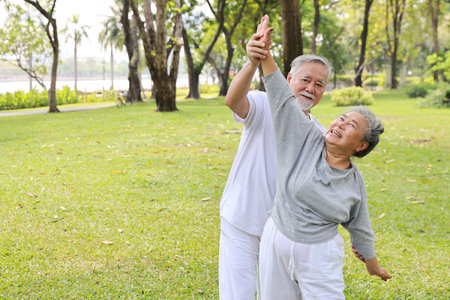 Asian senior couple practice yoga excercise, tai chi tranining, stretching and meditation together with relaxation for healthy in park outdoor after retirement. Happy elderly outdoor lifestyle conceptの写真素材