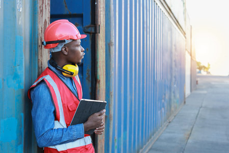 Foreman using tablet and walkie talkie radio control loading containers box. Engineer or worker with...