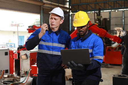 Professional heavy industry technician engineer in safety workwear maintenance and check part of robot arm machine in intelligent factory automotive. Industrial and technology support system conceptの写真素材