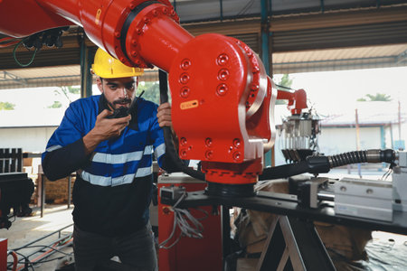 Professional heavy industry technician engineer in safety workwear maintenance and check part of robot arm machine in intelligent factory automotive. Industrial and technology support system conceptの写真素材