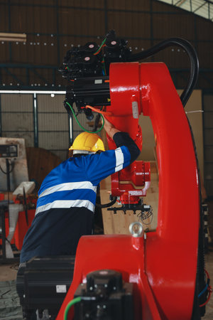 Professional heavy industry technician engineer maintenance and check part of robot arm machine in intelligent factory with computer and walkie talkie. Industrial and technology support system conceptの写真素材