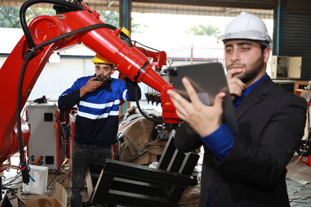 Professional heavy industry technician engineer in safety workwear and businessman maintenance and check part of robot arm machine with tablet in factory automotive. Industrial and technology conceptの写真素材