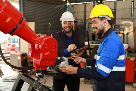 Professional heavy industry technician engineer in safety workwear and businessman maintenance and check part of robot arm machine with tablet in factory automotive. Industrial and technology conceptの写真素材