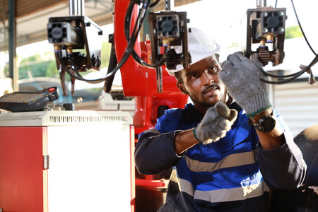 Professional heavy industry technician engineer in safety workwear and businessman maintenance and check part of robot arm machine with tablet in factory automotive. Industrial and technology conceptの写真素材
